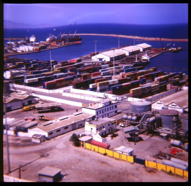 A sprawling view of a busy shipping port with numerous cargo containers and ships, illustrating the complexity and potential for delays in the distribution process.