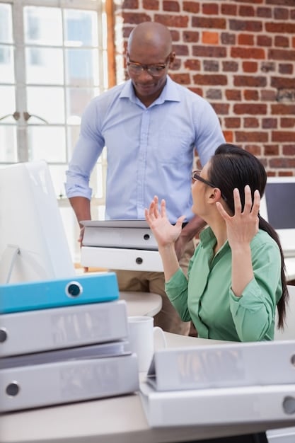 Photo of a publisher's office showing staff members looking stressed and overwhelmed, with piles of manga manuscripts and angry emails displayed on computer screens, illustrating the pressure and challenges faced during a major controversy.