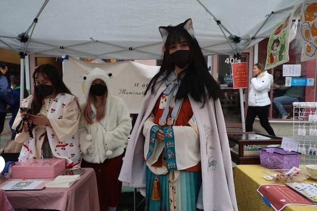 A bustling scene at an anime convention, with attendees browsing through tables filled with anime merchandise, cosplayers walking around, and an energetic atmosphere.