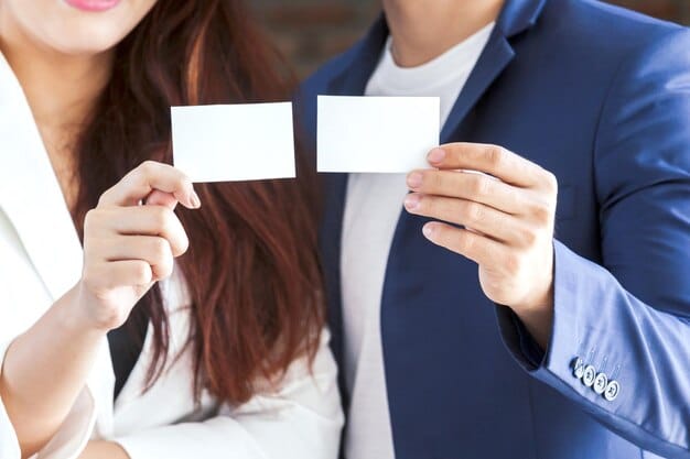 A photograph of a Japanese business meeting, showing individuals exchanging business cards (meishi) with careful attention to hierarchy and formality. The environment is modern, and the attire is formal business wear.