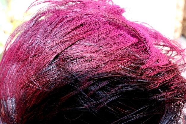A close-up of various styled wigs with different textures and colors, including wavy pastel pink, spiky bright red, and sleek dark blue, showcasing the diversity in wig styles.