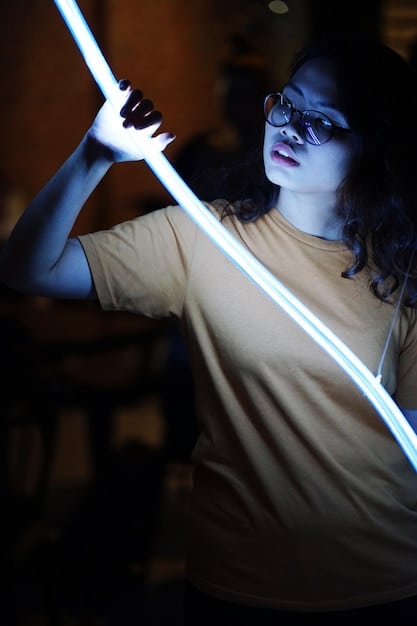 A detailed shot of a cosplayer attaching LED strips to a piece of armor. The cosplayer is carefully using adhesive to secure the LED strip along the edge of the armor. The image shows the precision and attention to detail required to seamlessly integrate LEDs into a costume piece.