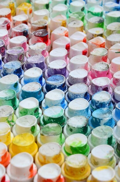 A close-up shot of various jars filled with colorful dye solutions. The image showcases a variety of shades and concentrations, illustrating the range of possibilities in fabric dyeing.