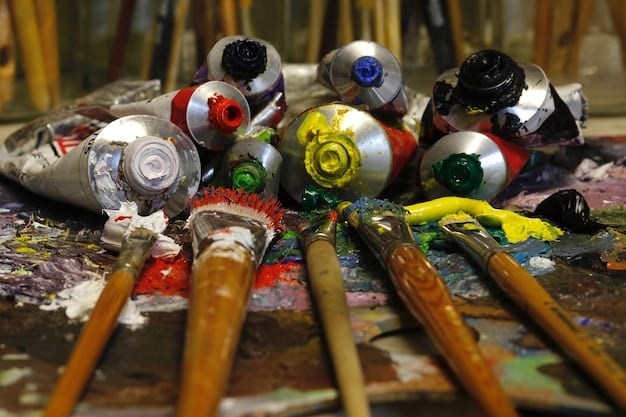 Various paintbrushes and airbrush equipment laid out next to a partially painted Worbla armor piece, showing intricate detail work in progress.